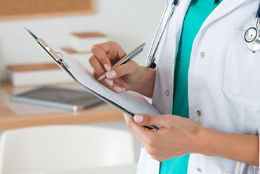 Female Physician writing on paper that is on a clipboard